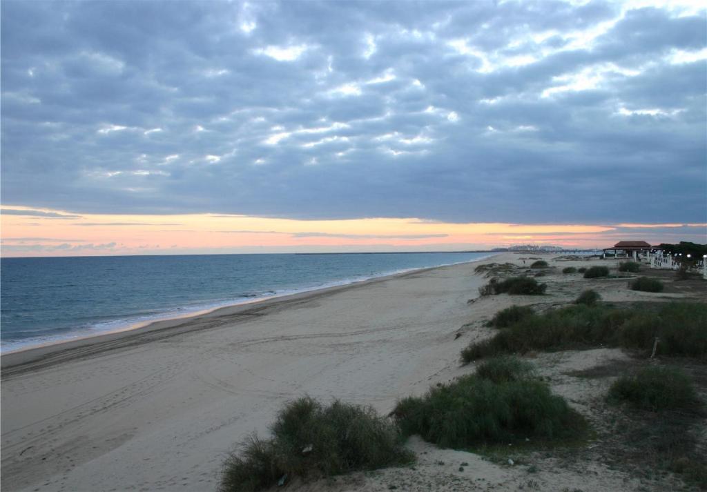 an empty beach with a cloudy sky and the ocean at PARAISO PLAYA Hotel in Isla Cristina