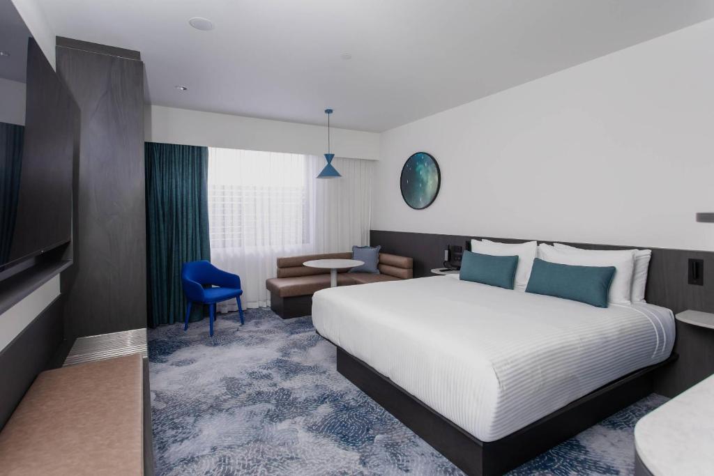 a hotel room with a large bed and a chair at Bayside Geelong Hotel & Apartments, an Ascend Collection Hotel in Geelong