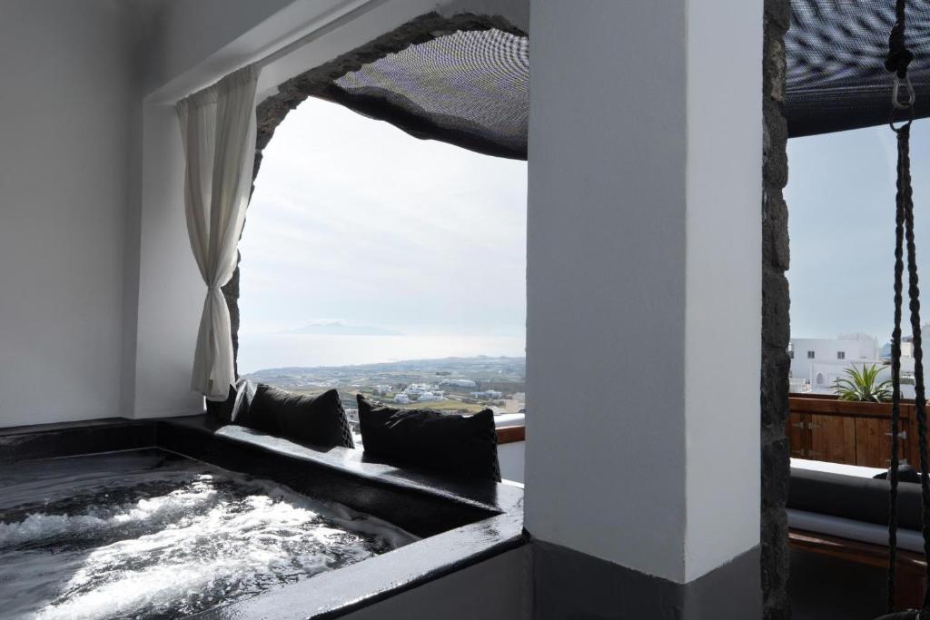 a bath tub in a room with a window at Lumera Suites in Firostefani