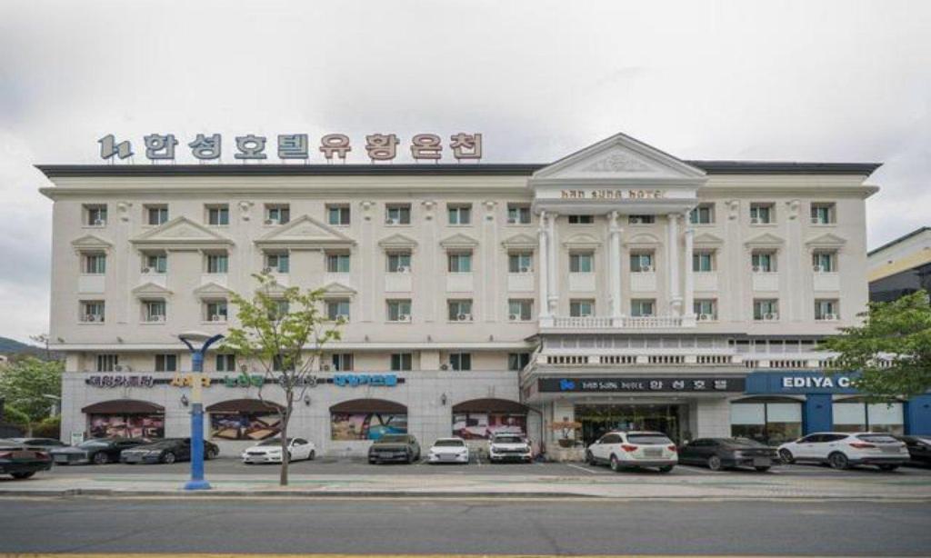 a large white building with cars parked in a parking lot at Bugok Hanseong Hotel in Changnyeong