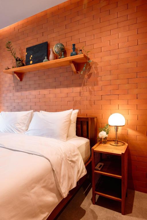 a bedroom with a bed and a brick wall at Easterly Room 01 in Chanthaburi