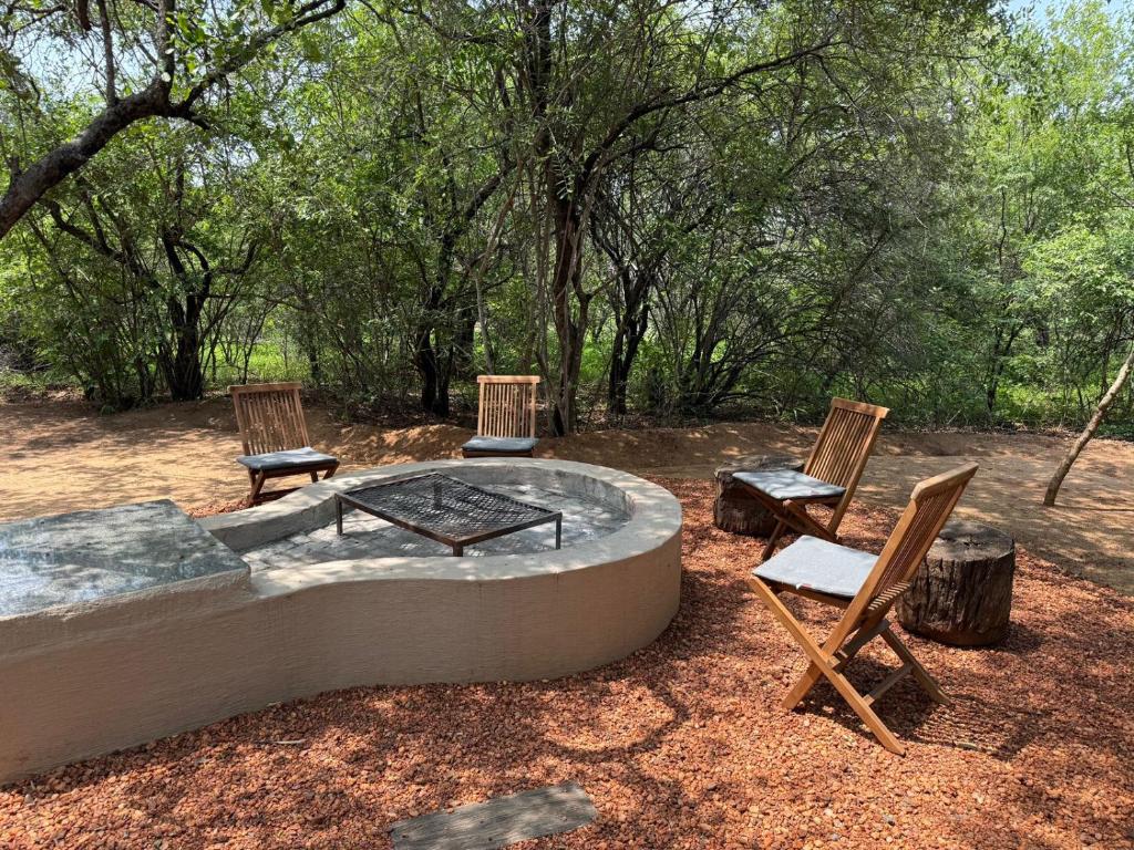 a fire pit with two chairs and a table and two chairs at Warthogs Rest in Hoedspruit