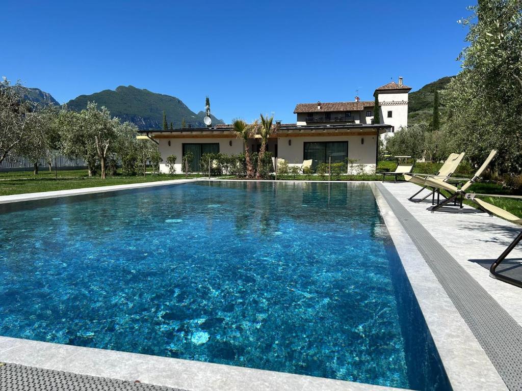 a swimming pool with blue water in front of a house at Oliveto Apartments in Riva del Garda
