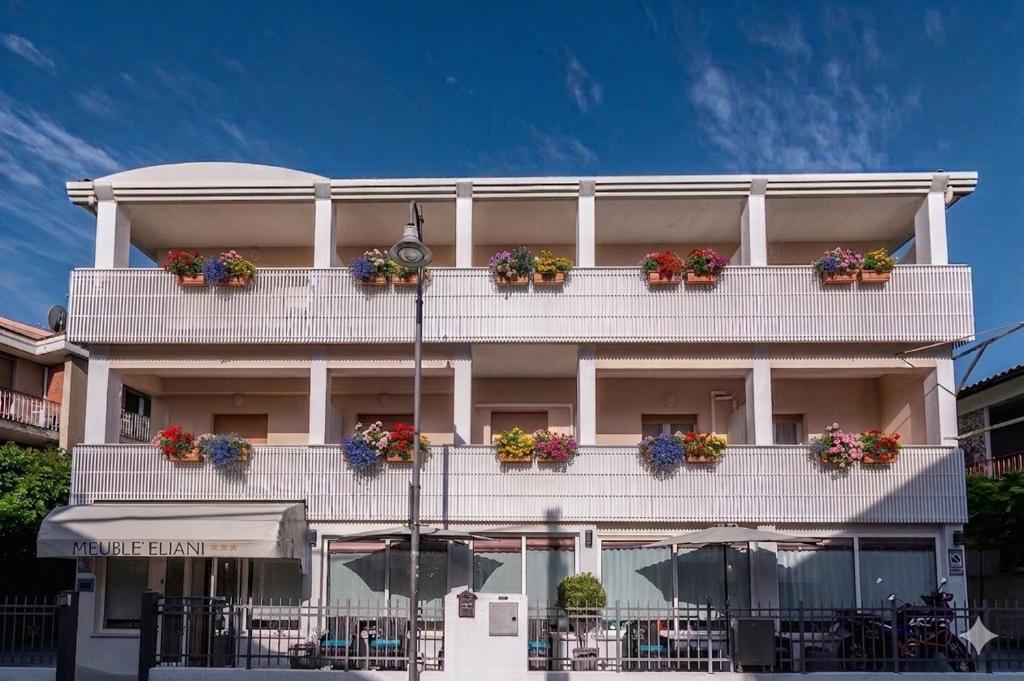 ein weißes Gebäude mit Blumenkästen auf den Balkonen in der Unterkunft Hotel Eliani in Grado
