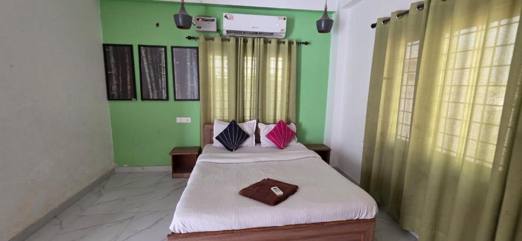 a bedroom with two beds and green walls at Hottel! Basera in Bhubaneshwar