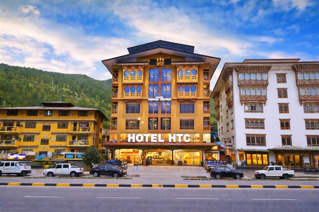 ein Hotelgebäude, vor dem Autos parken in der Unterkunft Hotel HTC , Thimphu in Thimphu