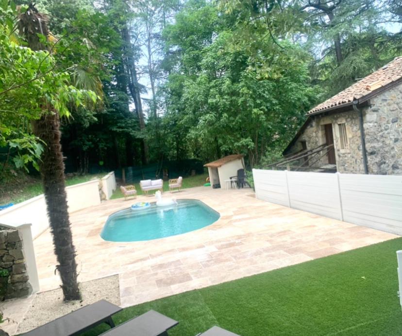 a backyard with a swimming pool and a fence at Le Mas des Sources - Appartement in Vals-les-Bains