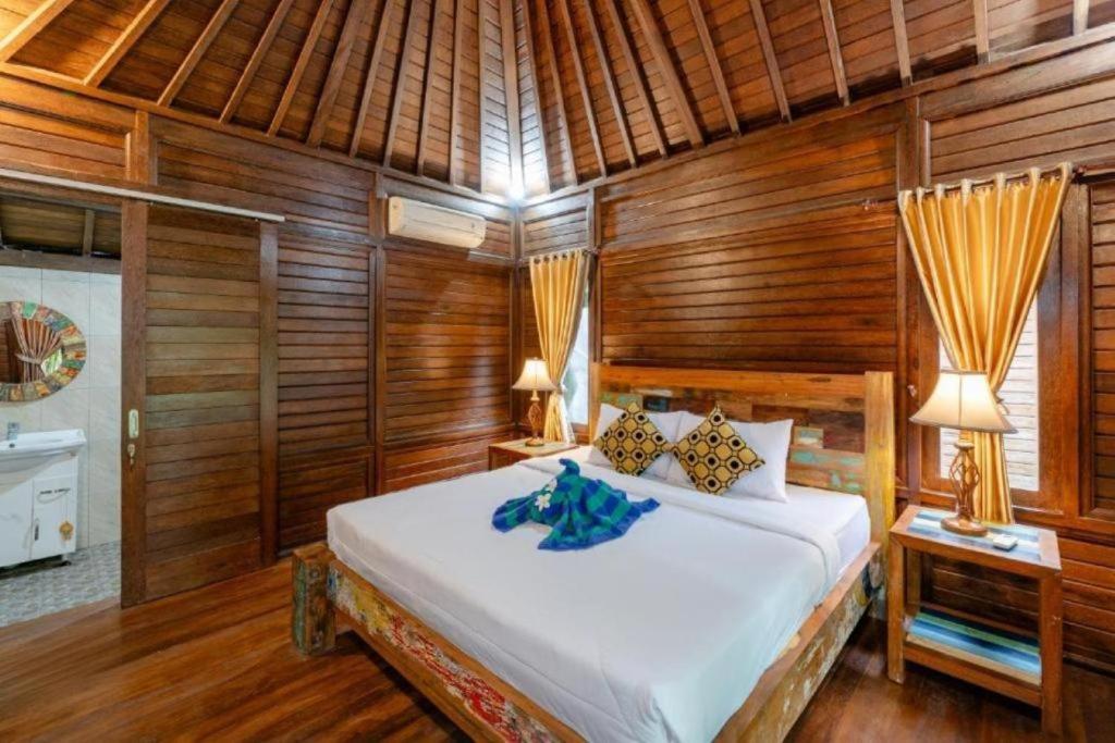 a bedroom with a bed in a room with wooden walls at Green Cottage Lembongan by ABM in Nusa Lembongan