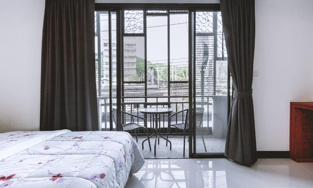 a bedroom with a bed and a table and a balcony at Ra Residence Phuket in Chalong 