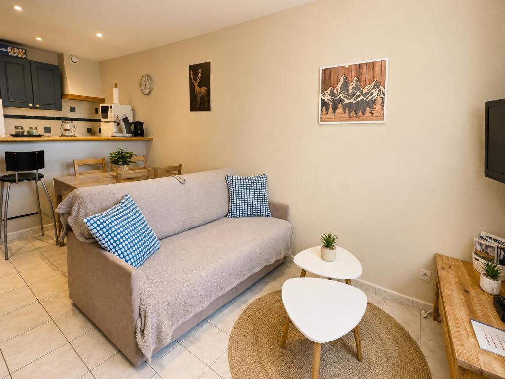 a living room with a couch and a kitchen at Grand Studio Tout Confort pour 3 personnes Linge en option in Barcelonnette