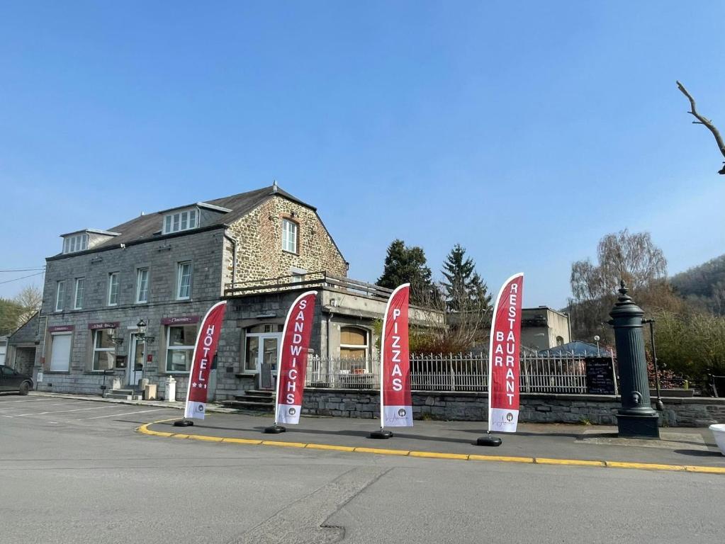 a building with red signs in front of a street at HOTEL L'AMERIVIERE*** in Aubrives