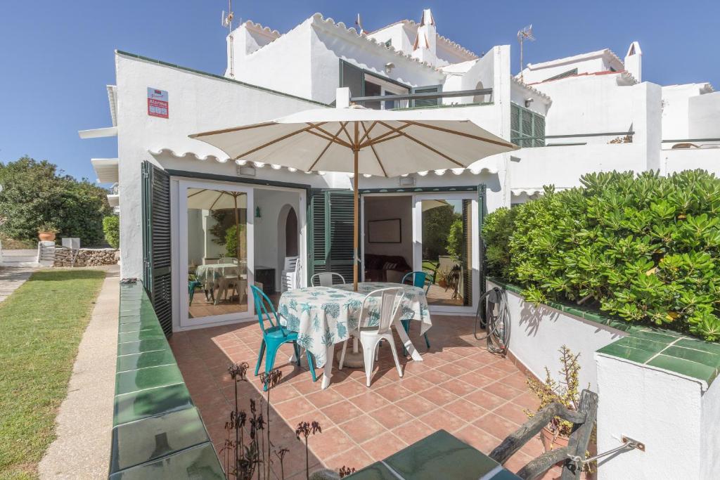 a patio with a table and an umbrella at Villa Sol del Este, Es Castell in Es Castell