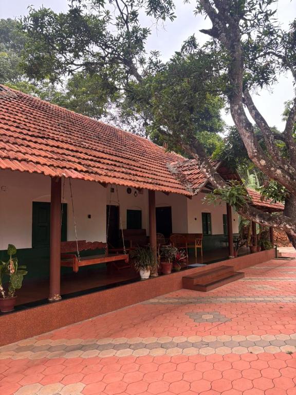 a house with a red roof and a patio at Ophel Ayurvedic Gardens, 7 Bed Heritage Home in Mananthavady