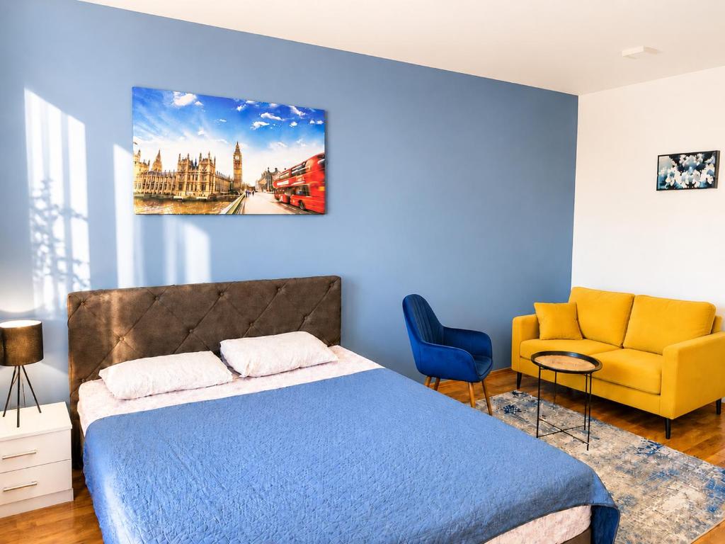 a bedroom with a bed and a yellow couch at Apartman Lanass Doboj in Doboj