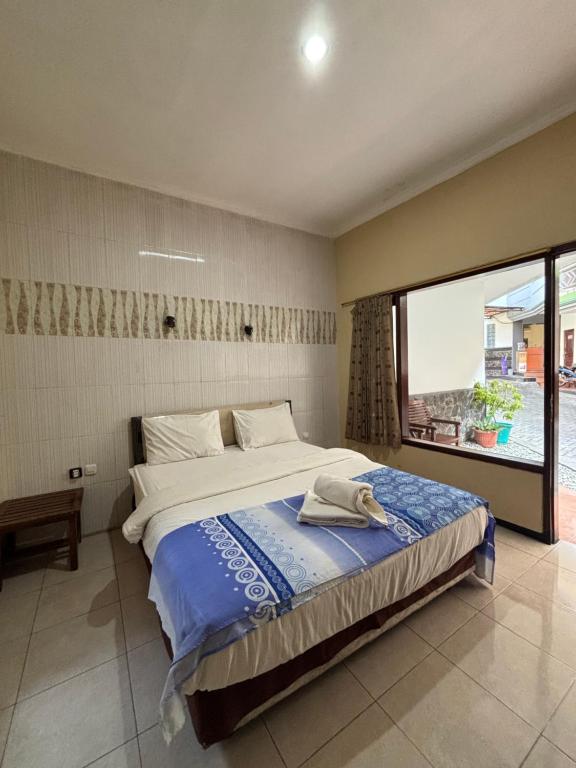 a bedroom with a large bed and a large window at Hotel Prima Asri 153 in Batu