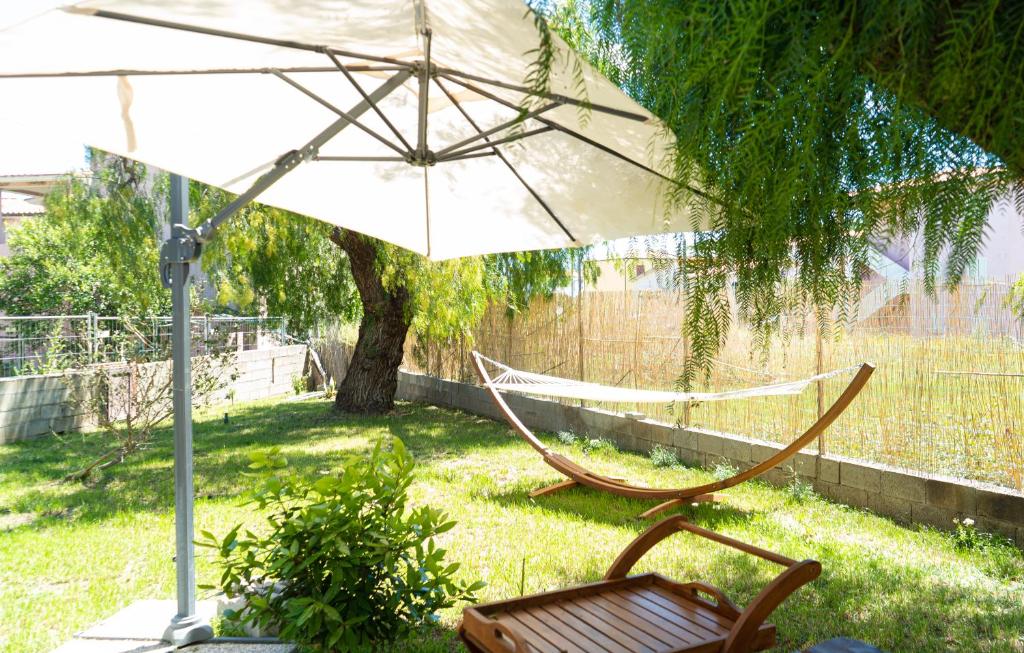a hammock and a chair under an umbrella in a yard at Il Pepe Rosa in Posada