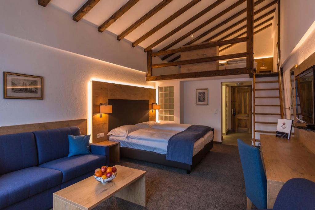 ツェルマットにあるAlpen Resort & Spaのベッドとソファとテーブルのある寝室