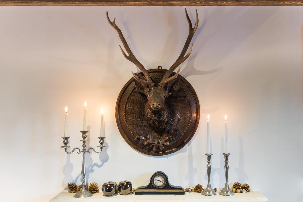 a clock with a deer head on a wall at Le Chalet Blanc in Megève