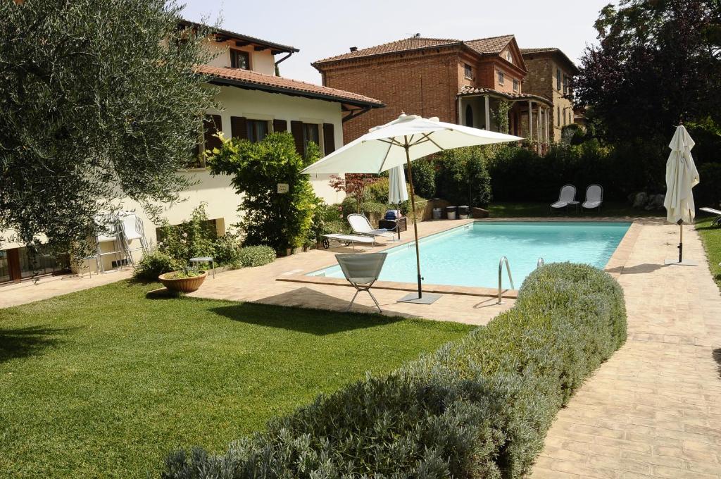 a pool with an umbrella and a chair and a table at Hotel Rutiliano in Pienza