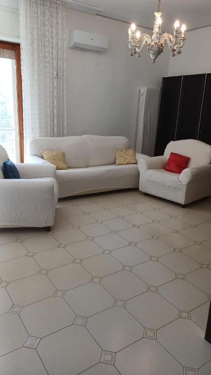 a living room with two white couches and a chandelier at Casa Carmela in Sapri