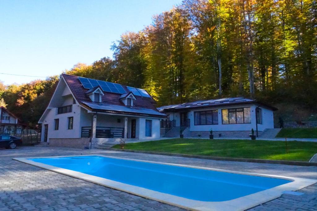 a house with a blue swimming pool in front of a house at Dey Villa, Valea Avrigului, Transilvania in Avrig
