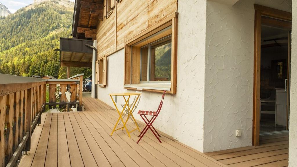 a deck with a red chair and a window at Chalet authentique à Ovronnaz in Leytron