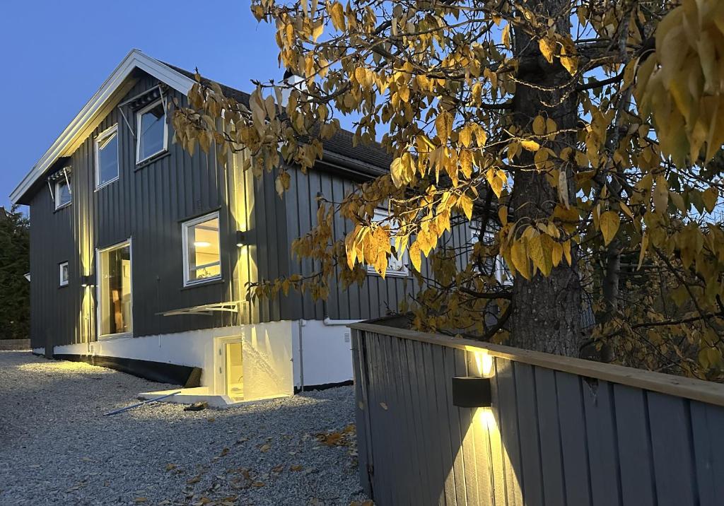 a black house with a tree and a fence at Flott sommerhus midt i Lillehammer sentrum in Lillehammer