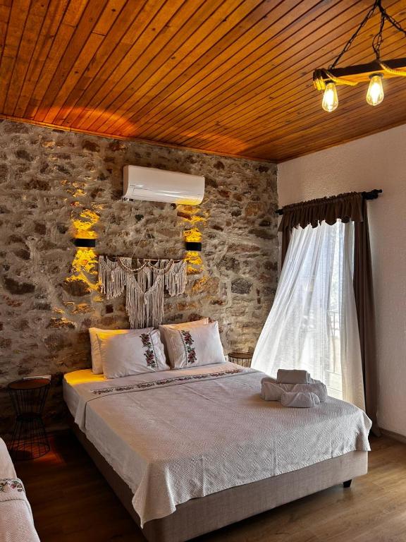 a bedroom with a bed and a stone wall at Chori Avlu Küçükköy in Ayvalık
