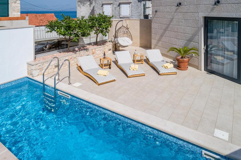 a patio with chairs and a swimming pool at VILLA STONE PEARL SUTIVAN - exceptional luxury new three-room villa - private pool and jacuzzi - perfect location right next to the town center and the beach - secured parking space in Sutivan