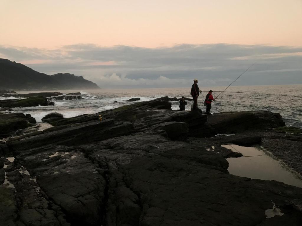 a couple of people fishing on the rocks near the ocean at Dali Yi International Hostel in Toucheng