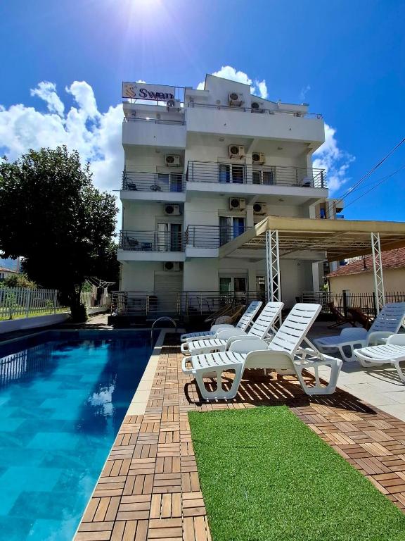 a hotel with a swimming pool and white lounge chairs at Villa Swan in Bar