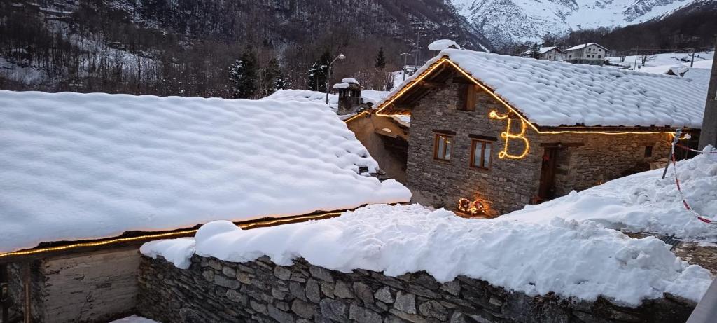 a house covered in snow with lights on it at Lu Biulè di Pau in Groscavallo