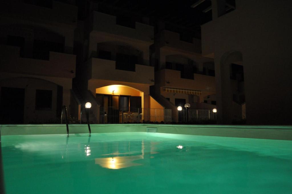 een leeg zwembad 's nachts met een gebouw bij La rosa dei venti in Lu Razzoni