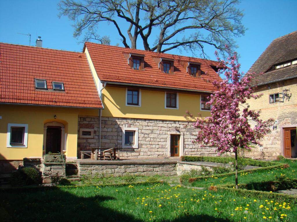 uma casa amarela com um telhado vermelho e uma árvore em Martinkovice 201 Broumov em Martínkovice