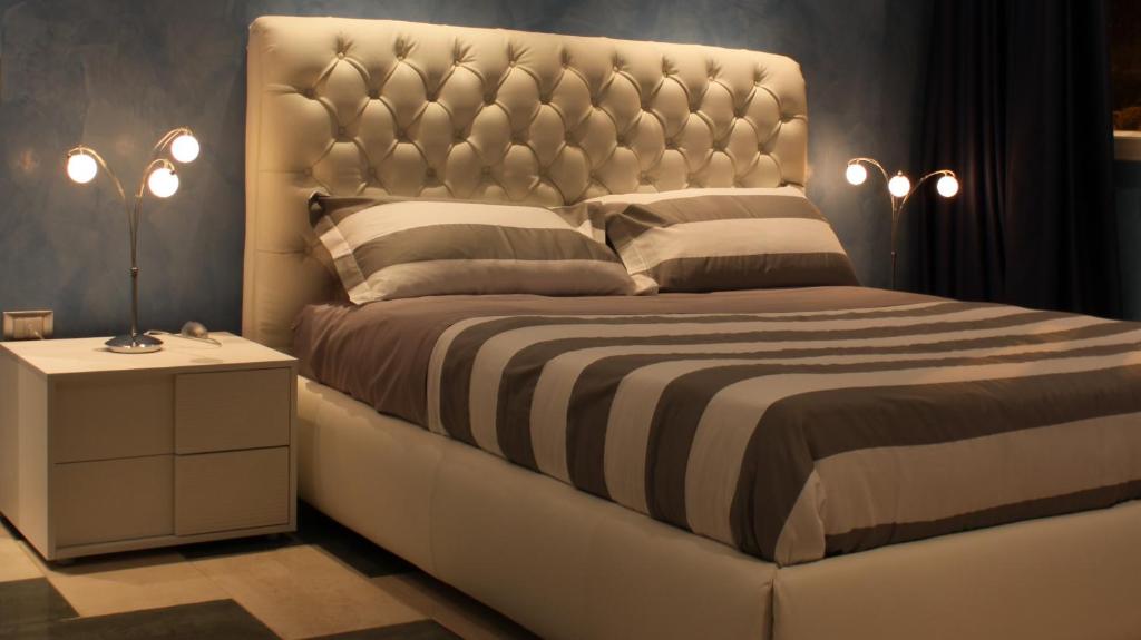 ein Schlafzimmer mit einem großen Bett mit einem großen Kopfteil in der Unterkunft Central Rooms in Noto Marina