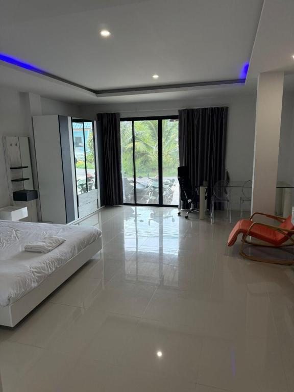 a white bedroom with a bed and a desk and chairs at Sleek Modern Studio in Rawai, Phuket in Ban Saiyuan (1)