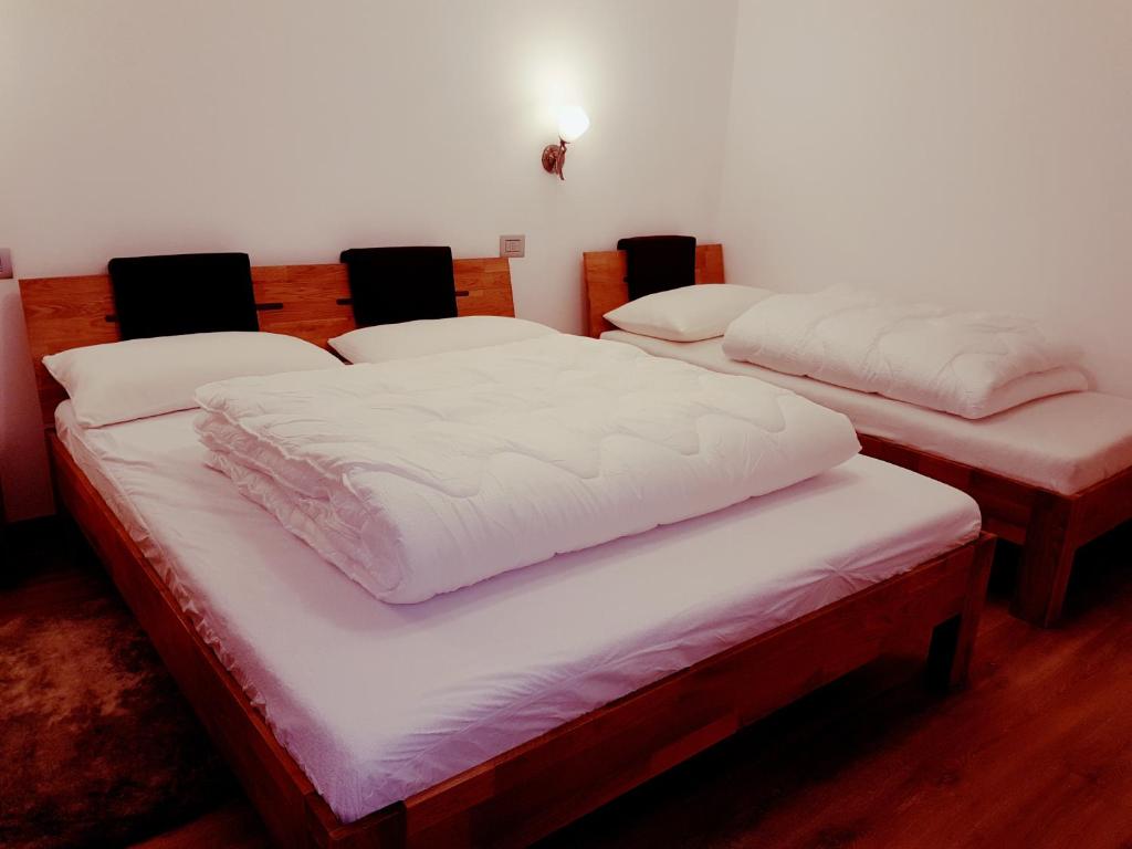 drie bedden in een kamer met witte lakens bij Apartment San Colombano in Valdidentro