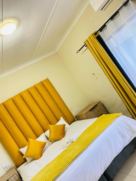 a bedroom with a bed with yellow pillows and a window at Nvivi boutique hotel in Polokwane