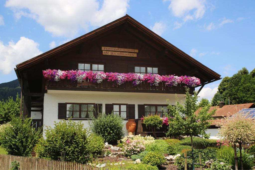ein Haus mit Blumen auf dem Balkon in der Unterkunft Ferienwohnungen am Buchbrunnen in Pfronten