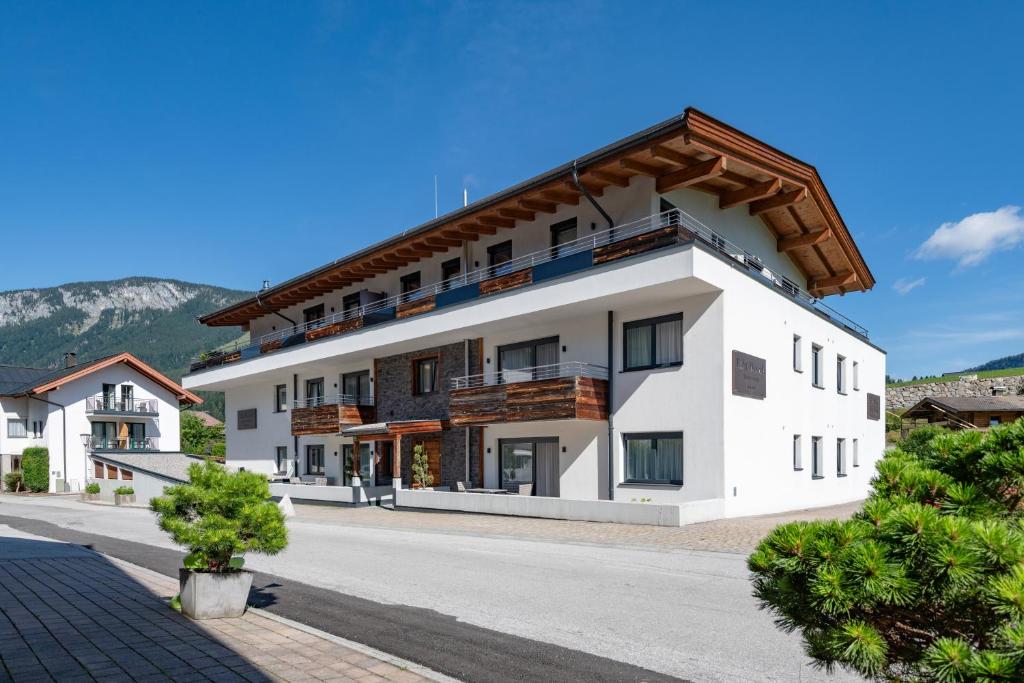 a large white building with a brown roof at Echt Woods Appartements in Söll