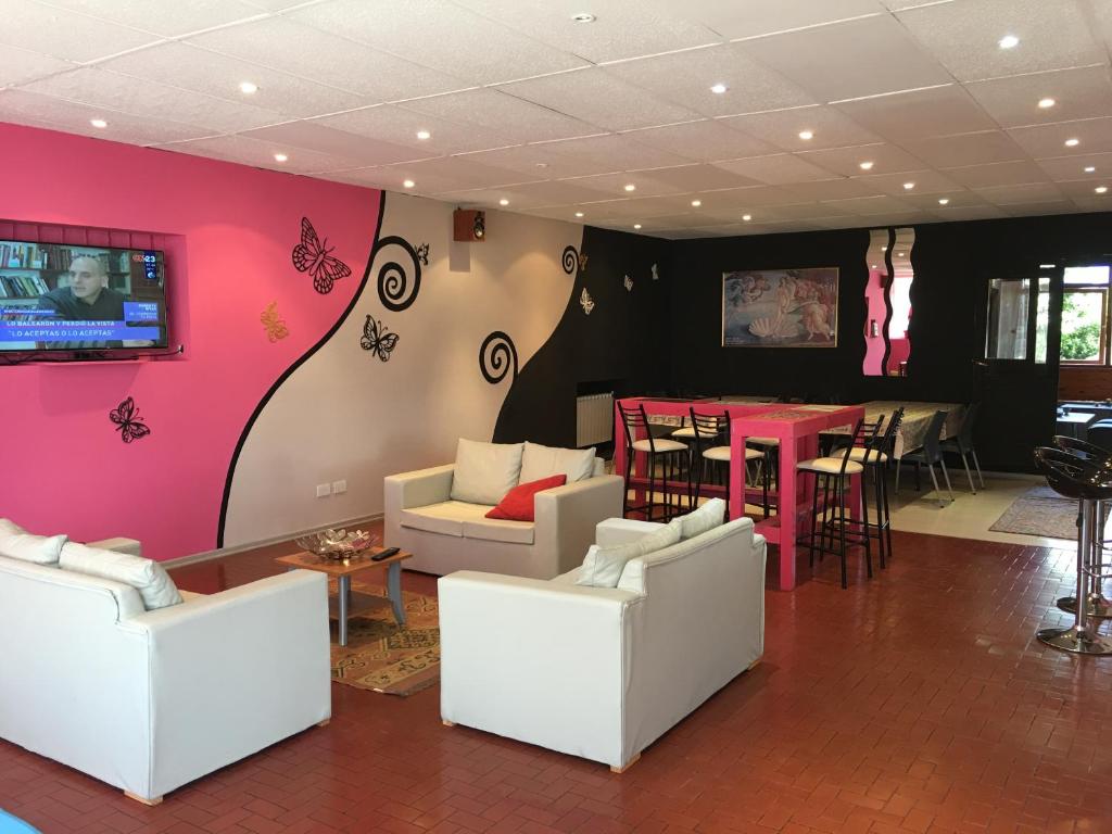 una sala de estar con muebles blancos y una pared de color rosa. en Italia Inn Hostel en San Carlos de Bariloche