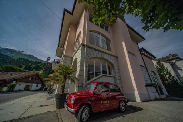 a red car parked in front of a house at GRAND your home with common kitchens with self check-in in Engelberg
