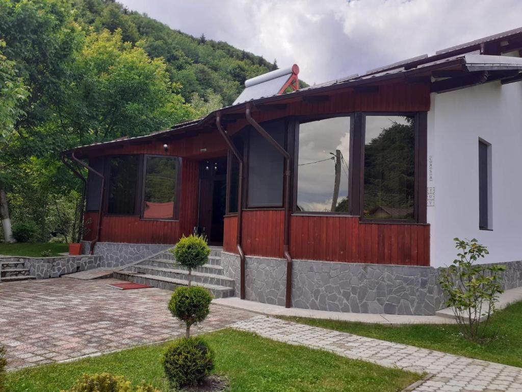 a home with a red and white building at La Păstrăvărie ,,Casa Iov,, in Moroeni