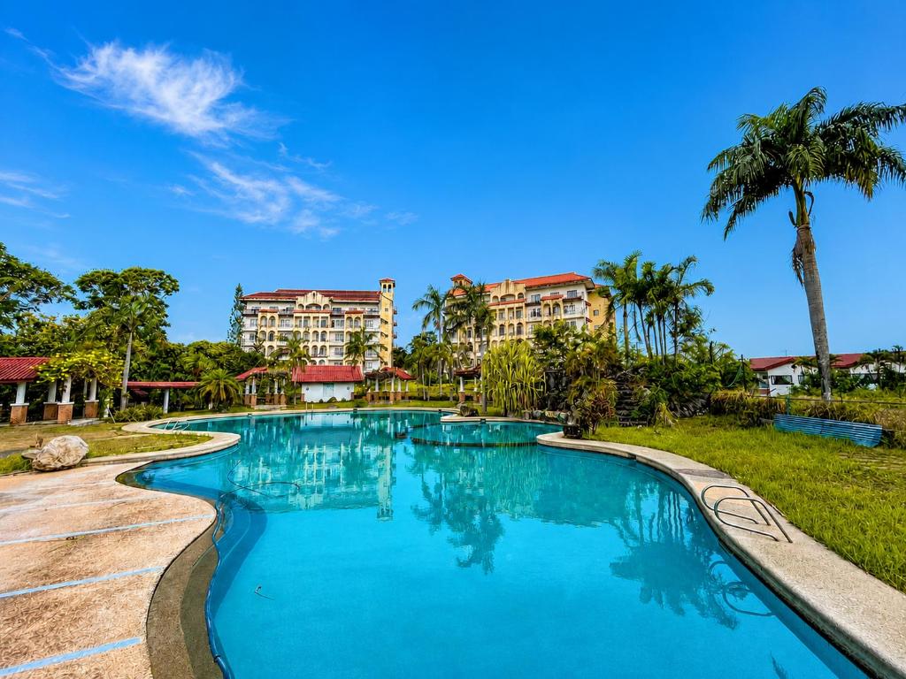 a swimming pool at a resort with palm trees and buildings at Graceland Resort Tayabas Quezon in Tayabas
