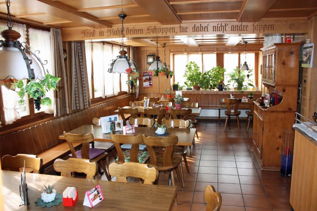ein Restaurant mit Holztischen, Stühlen und Fenstern in der Unterkunft Hotel Restaurant Koi-Gartenteich in Hausernmoos