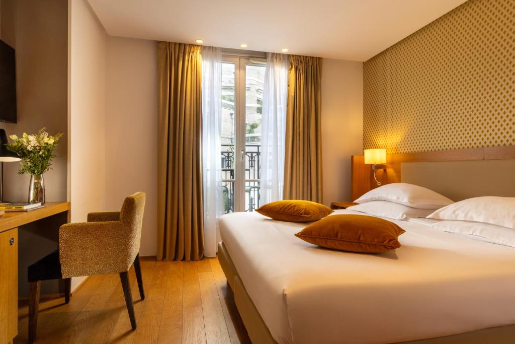 ein Hotelzimmer mit zwei Betten, einem Schreibtisch und einem Fenster in der Unterkunft Hotel Le Six in Paris