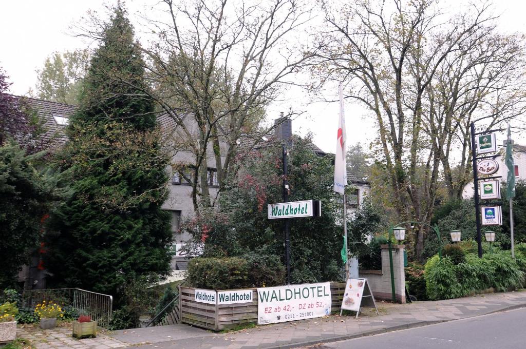 ein Straßenschild vor einem Garten mit Bäumen in der Unterkunft Waldhotel Unterbach in Düsseldorf