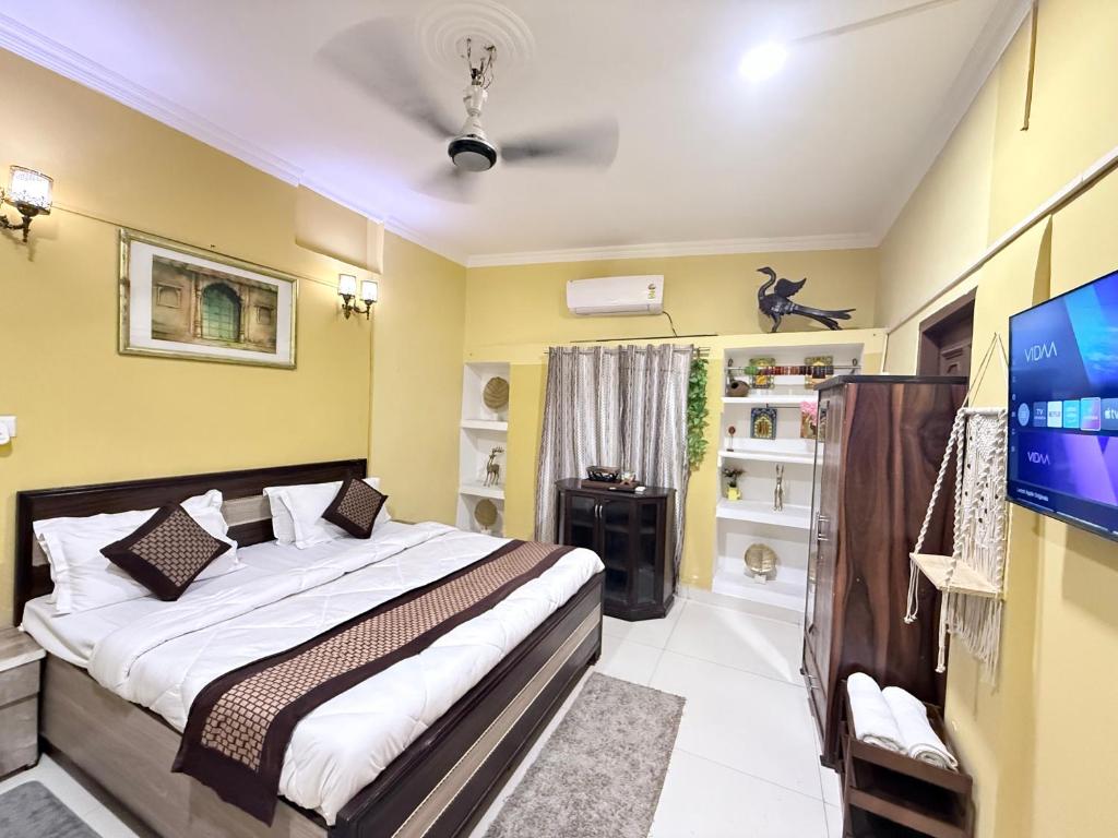 a bedroom with a bed and a flat screen tv at Staylo Suites Edit in New Delhi