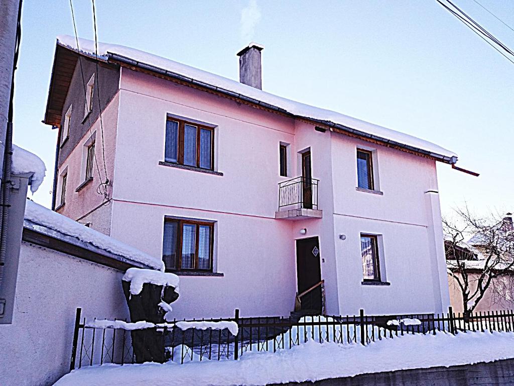 una casa rosa en la nieve con una valla en Guest House AHP, en Mala Tsŭrkva