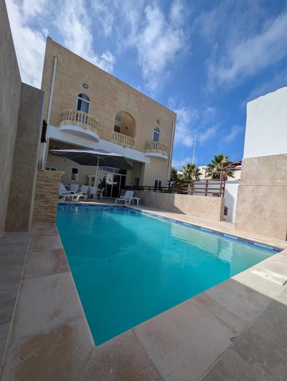 a large swimming pool in front of a building at Ta Robert Farmhouse in San Lawrenz